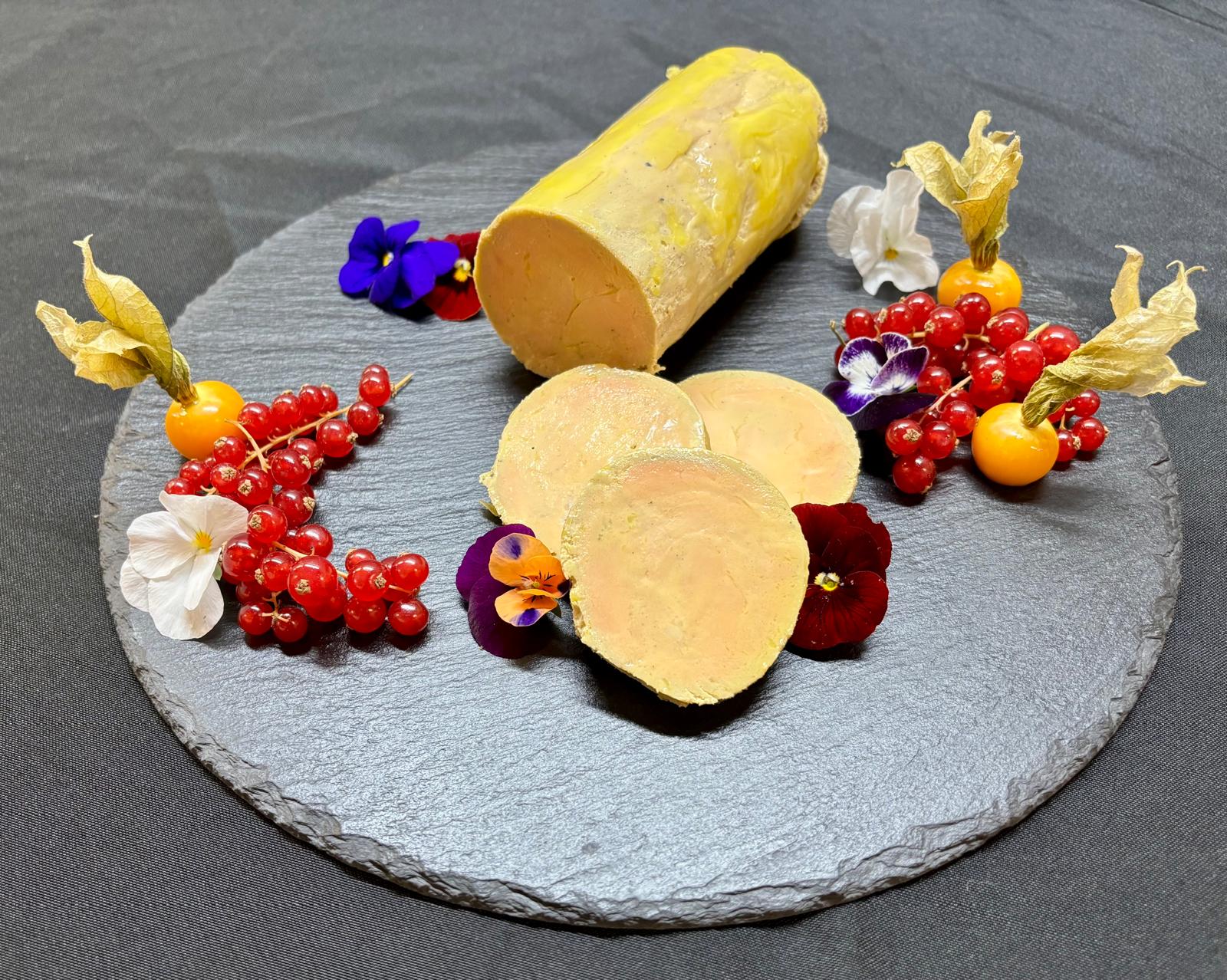ballottine de foie gras de canard fait maison traiteur mis en valeur sur planche d'ardoise avec des fleurs comestibles et fruits rouges
