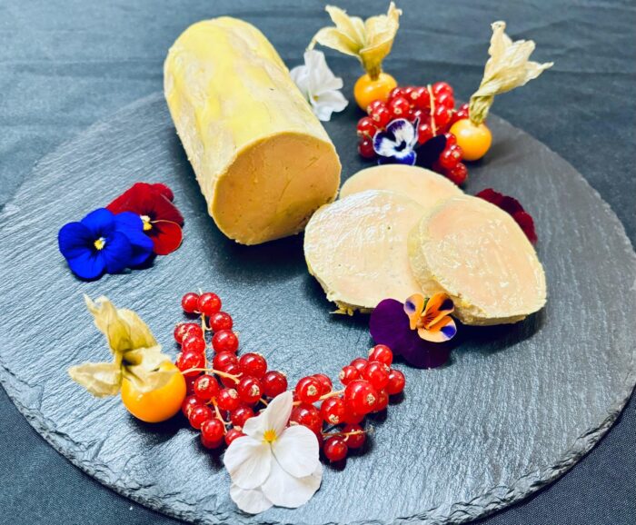bloc de foie gras préparé par votre traiteur à Nyon, présenté sur ardoise avec fleurs comestibles, groseilles et physalis